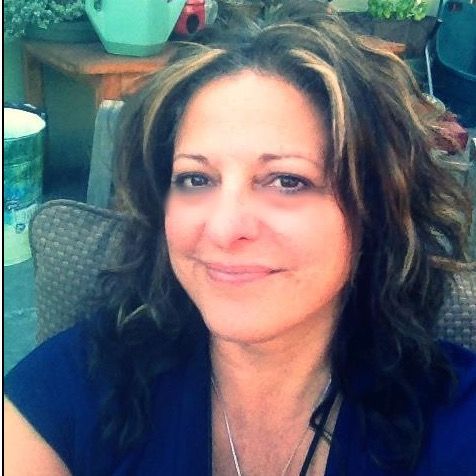 A woman in a blue shirt is smiling for the camera - Linda Weilert