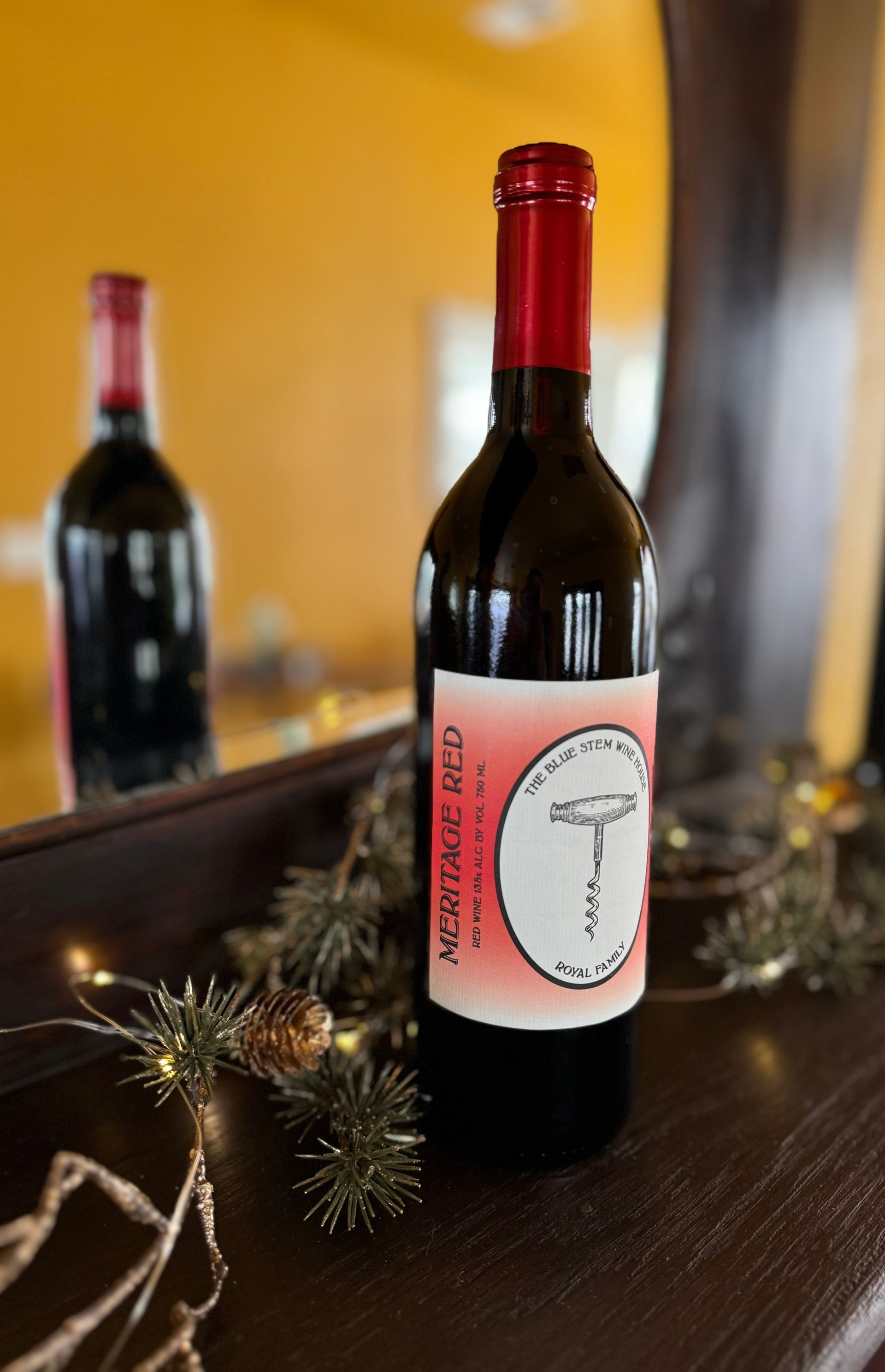 A bottle of meritage red wine is sitting on a table in front of a mirror.