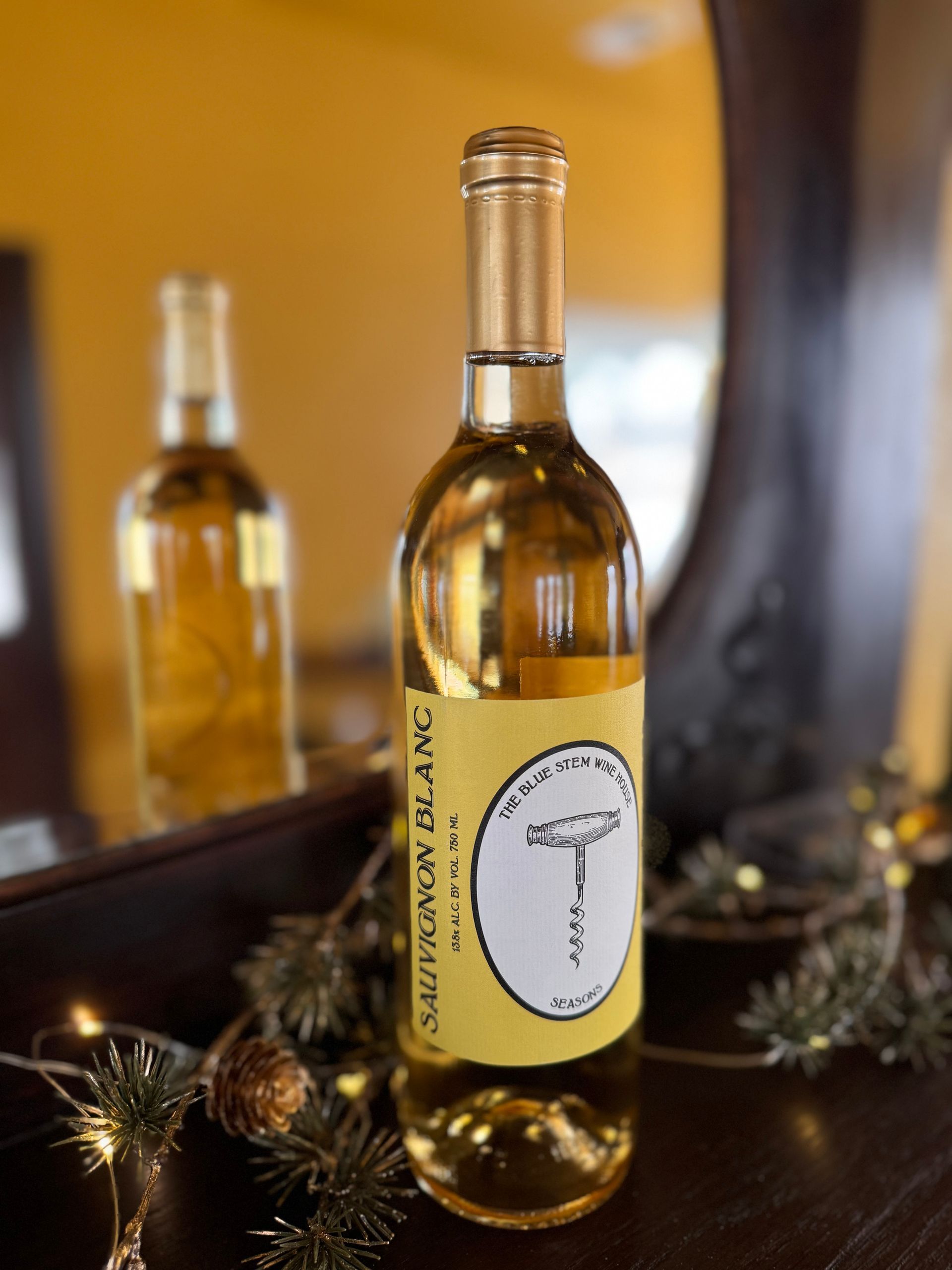 A bottle of sauvignon blanc wine is sitting on a table in front of a mirror.
