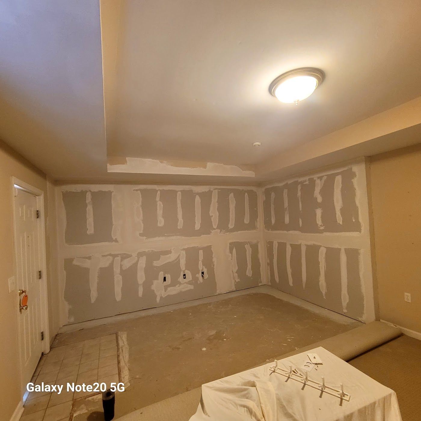 Room under construction, drywall installed, unfinished ceiling, tan walls, exposed wires.