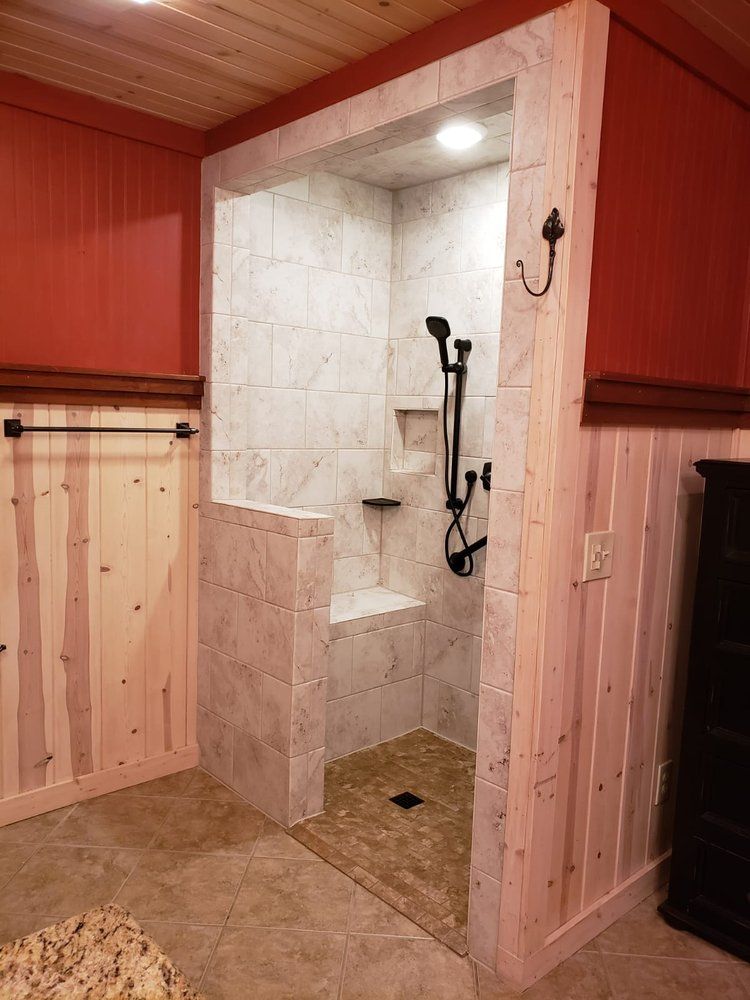 A walk-in shower with tiled walls and floor, and a built-in seat, set into a red-walled bathroom.