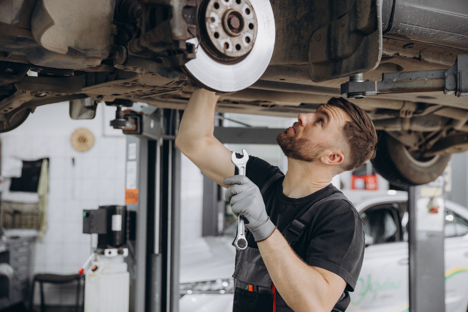 Mechanic inspecting a car’s undercarriage while it’s lifted on a repair hoist
