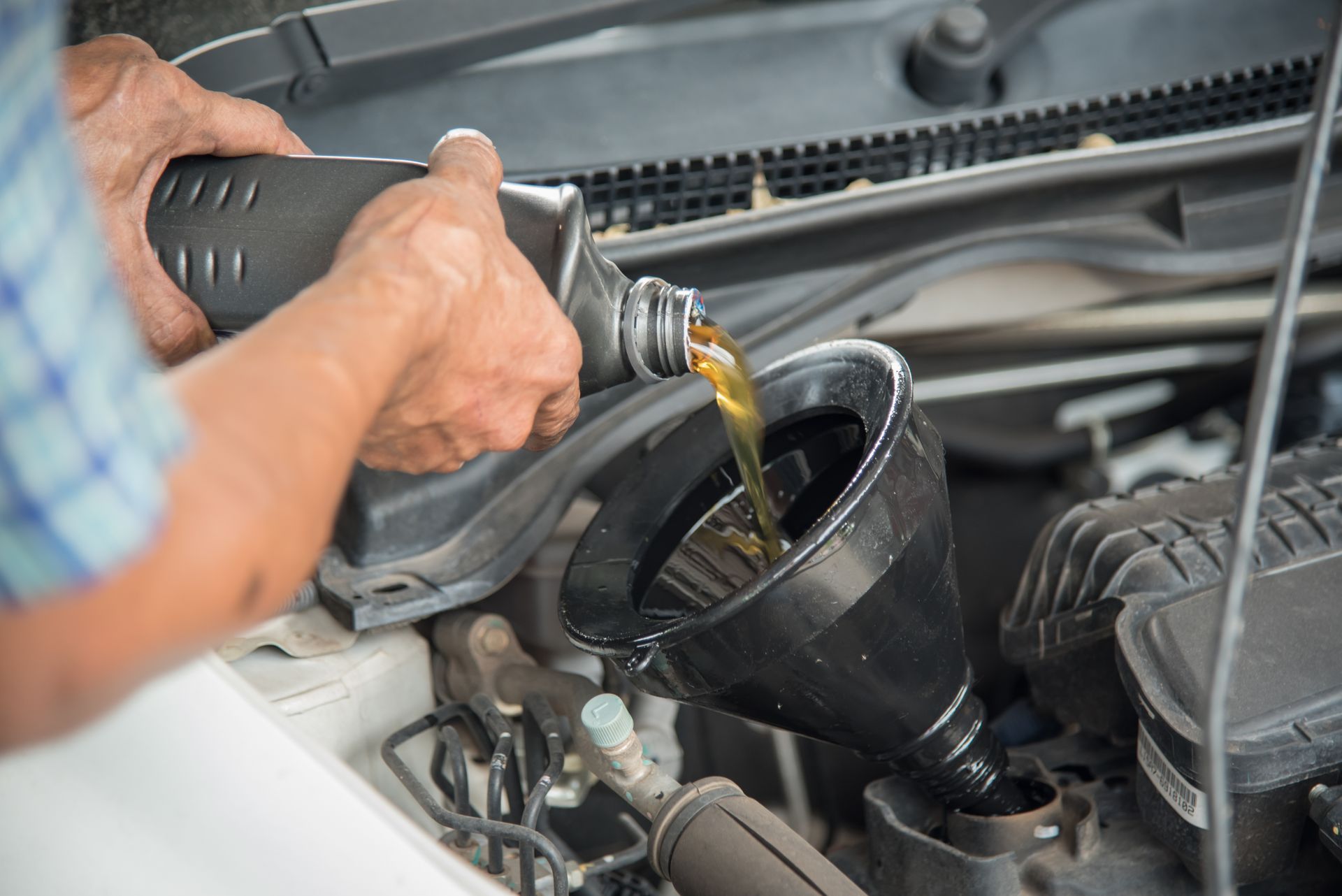 Pouring motor oil into a car engine through a funnel