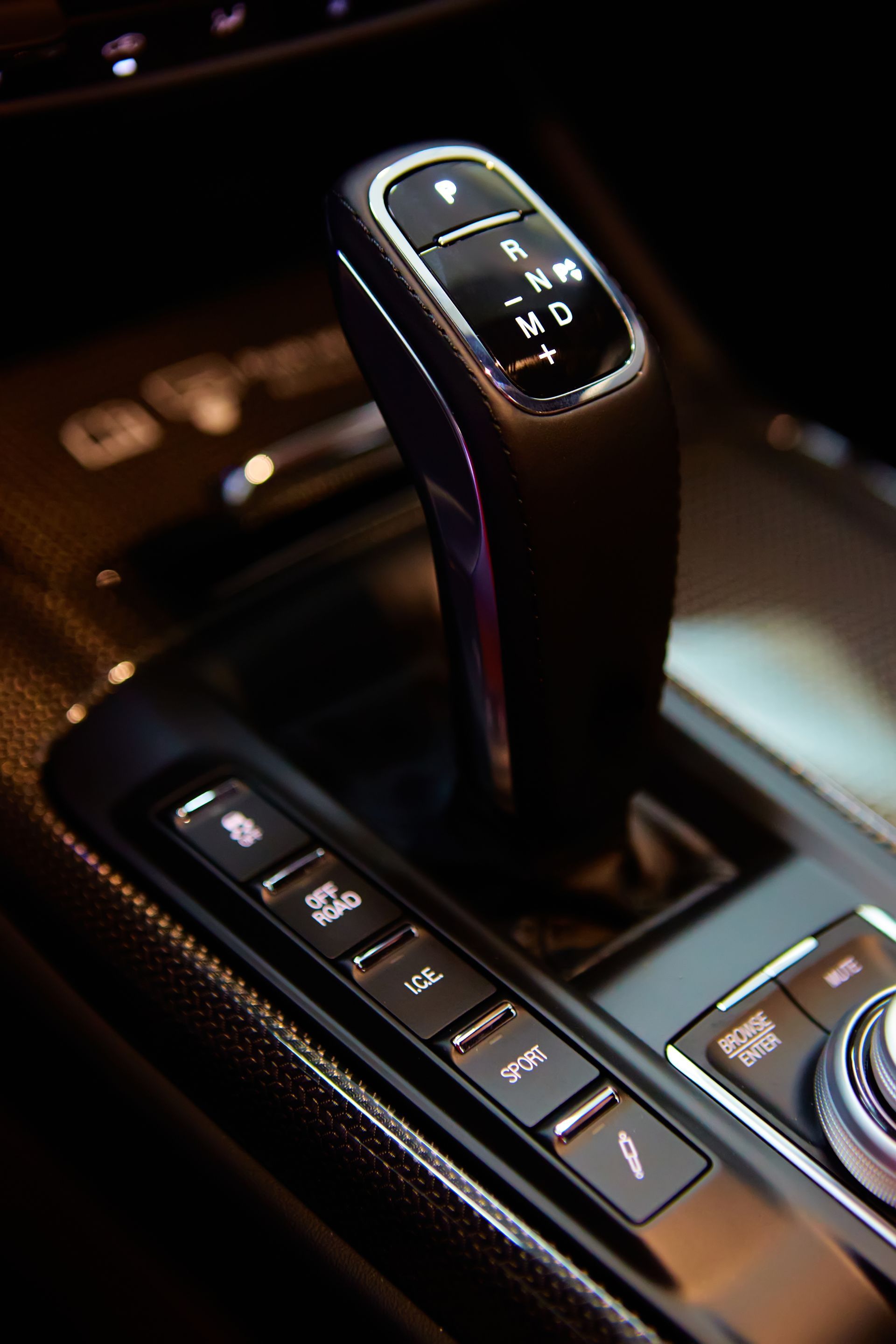 Close-up of a luxury car gear selector and dashboard buttons in a dark interior