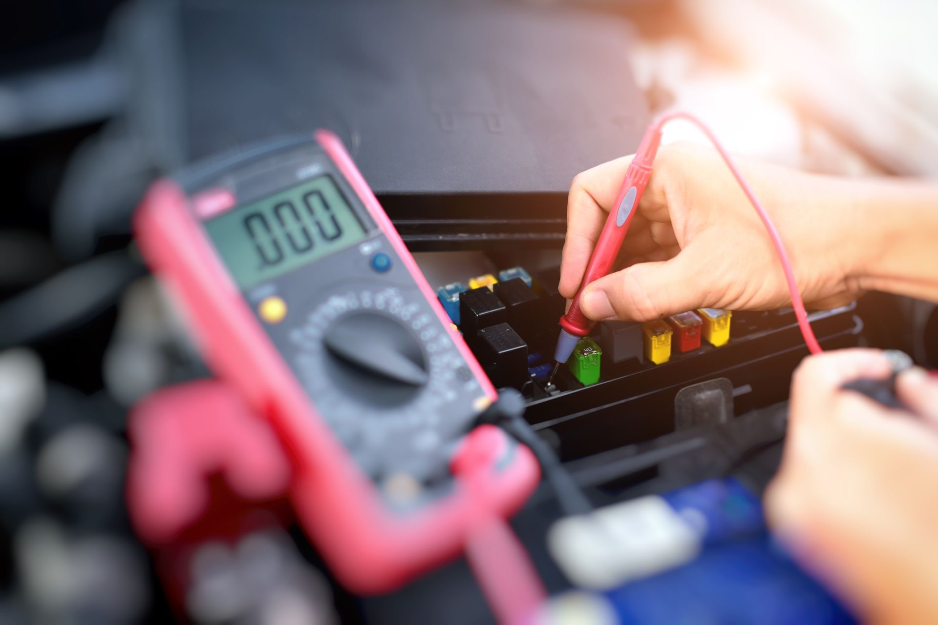 Technician testing electronics with a multimeter and probes inside an open device