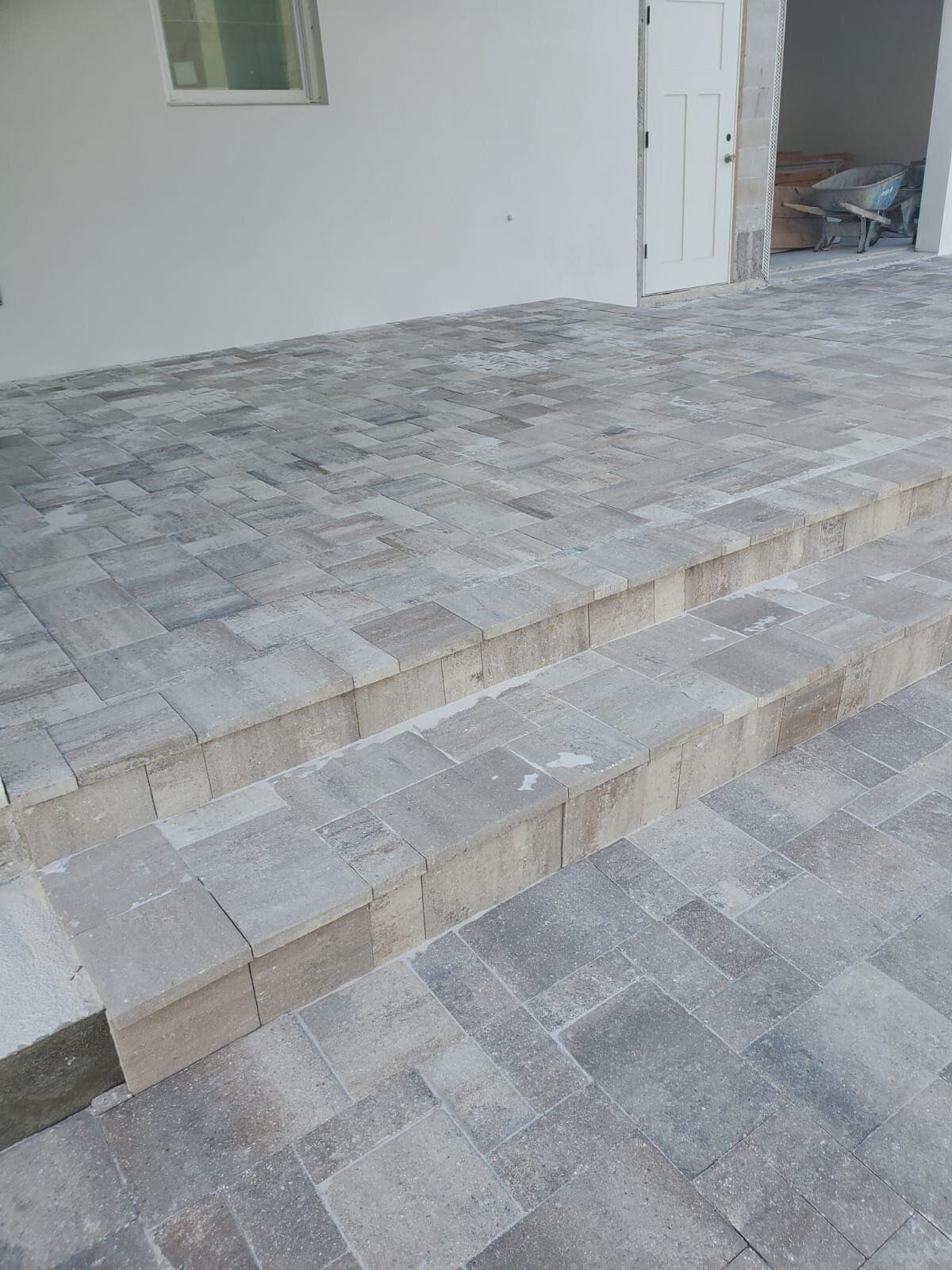 Gray stone-tiled steps and patio beside a house exterior with an open doorway
