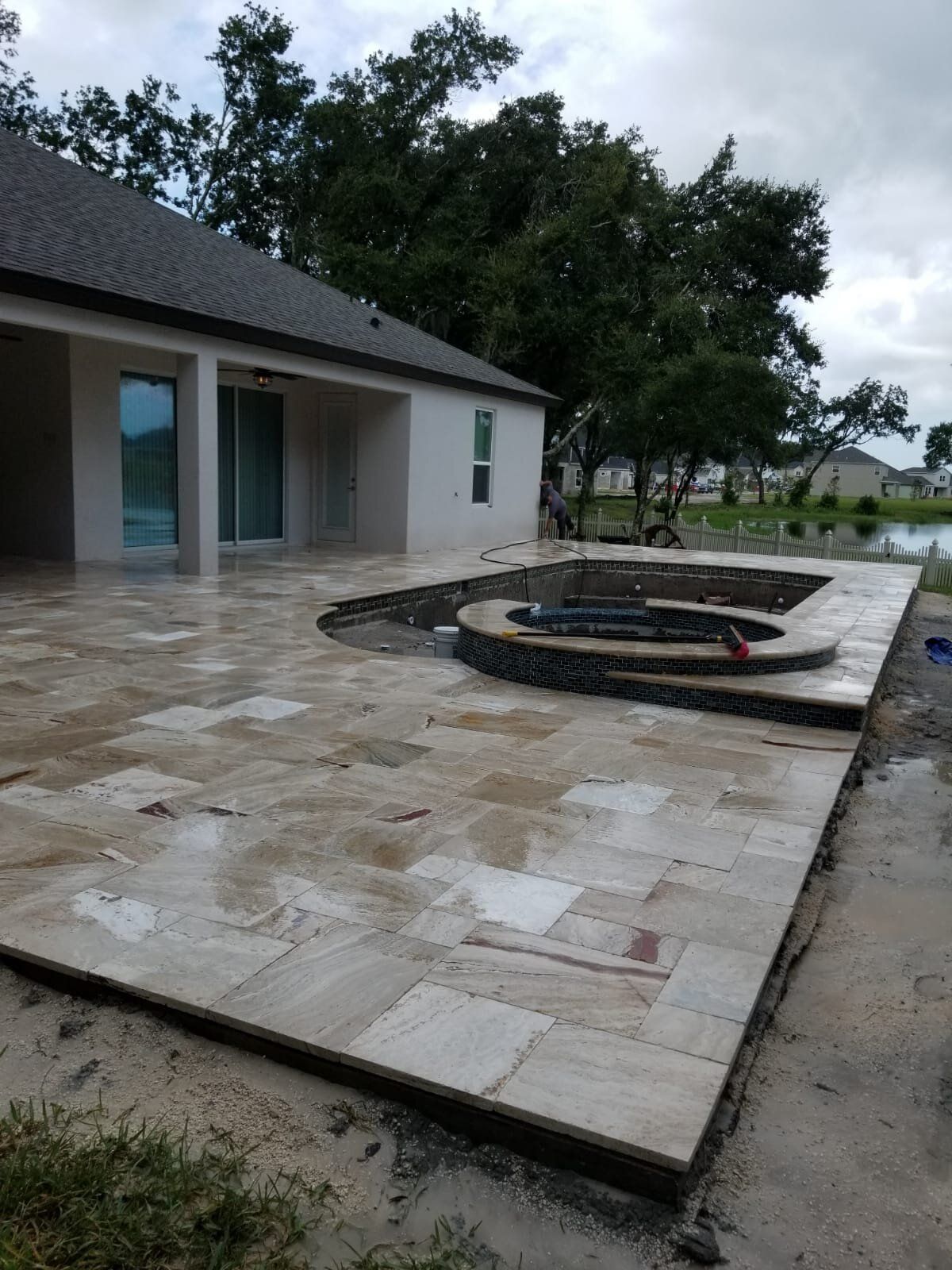 Stone patio beside a house with a circular fire pit and trees in the background