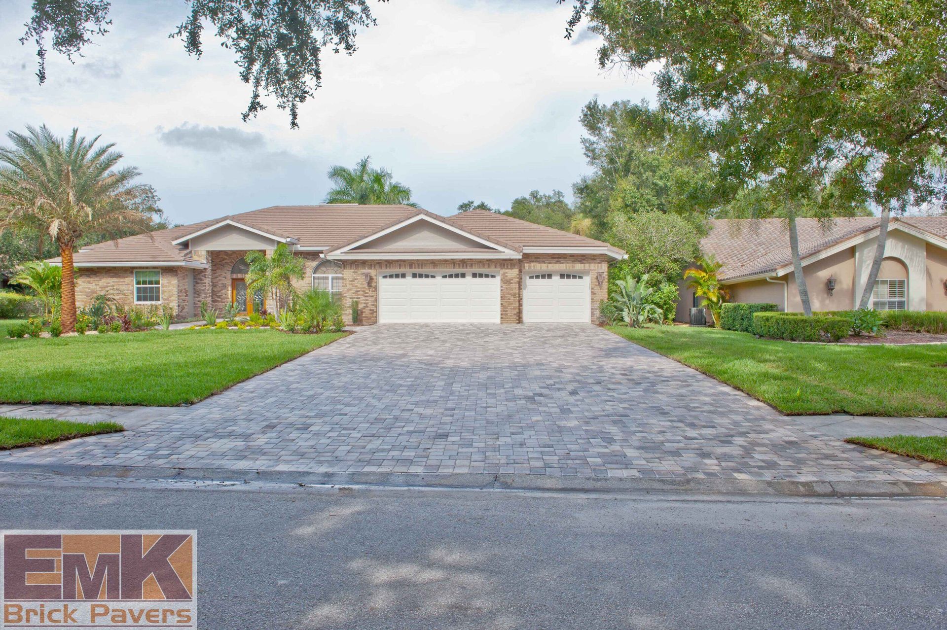 Single-story brick house with a three-car garage and long paved driveway, viewed from the street