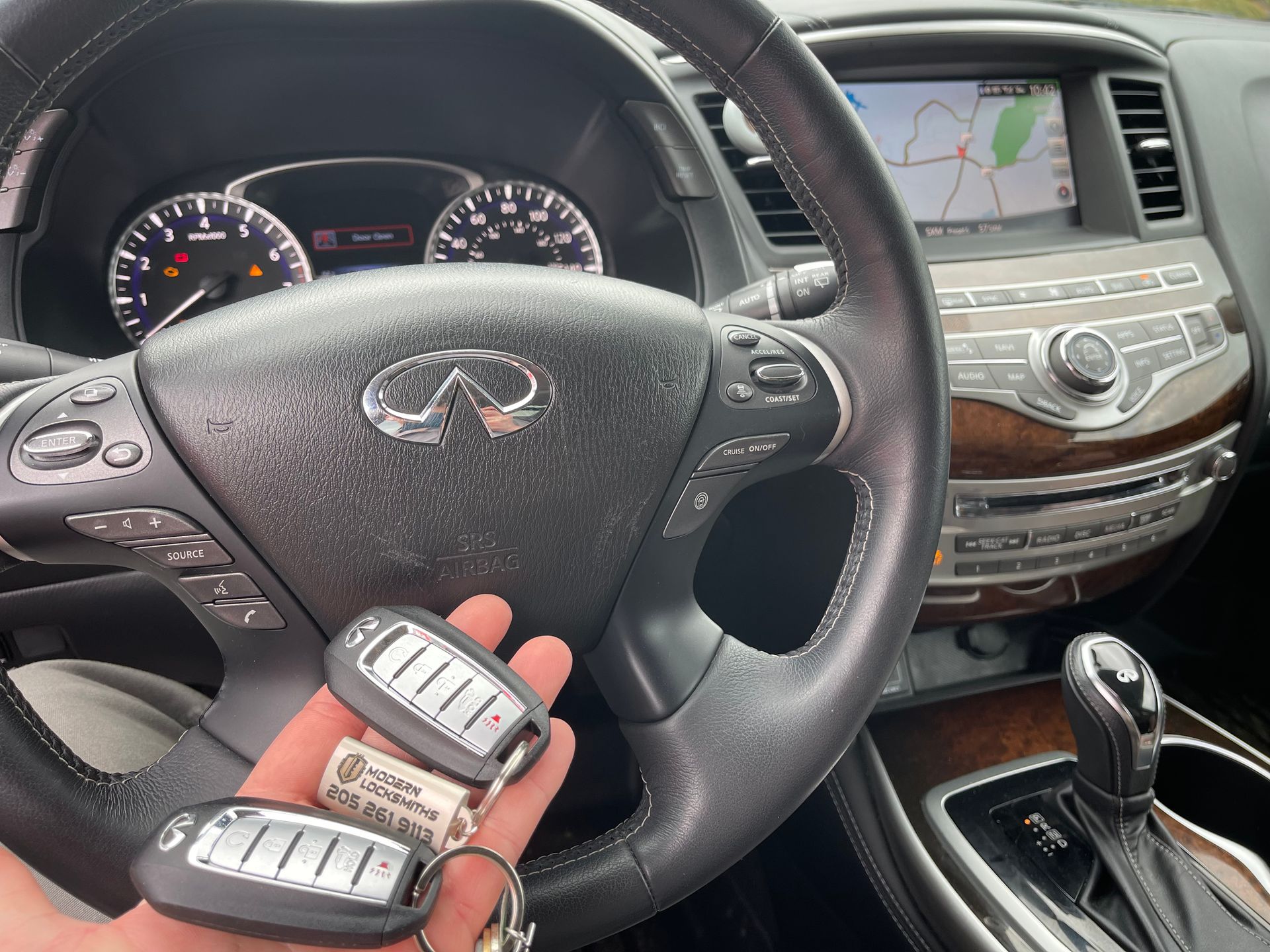 a hand holding a key in front of a car