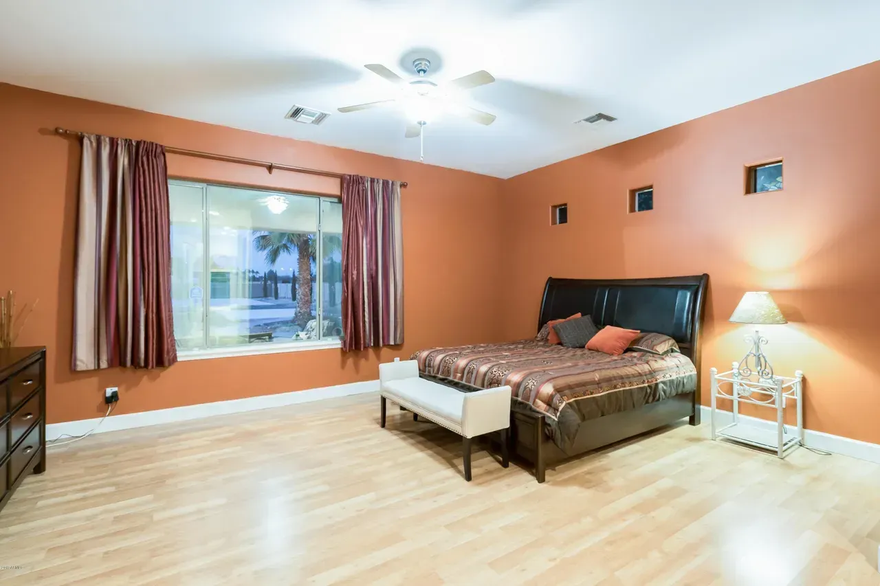 Bright bedroom with orange walls, king bed, window seat, and bedside lamp