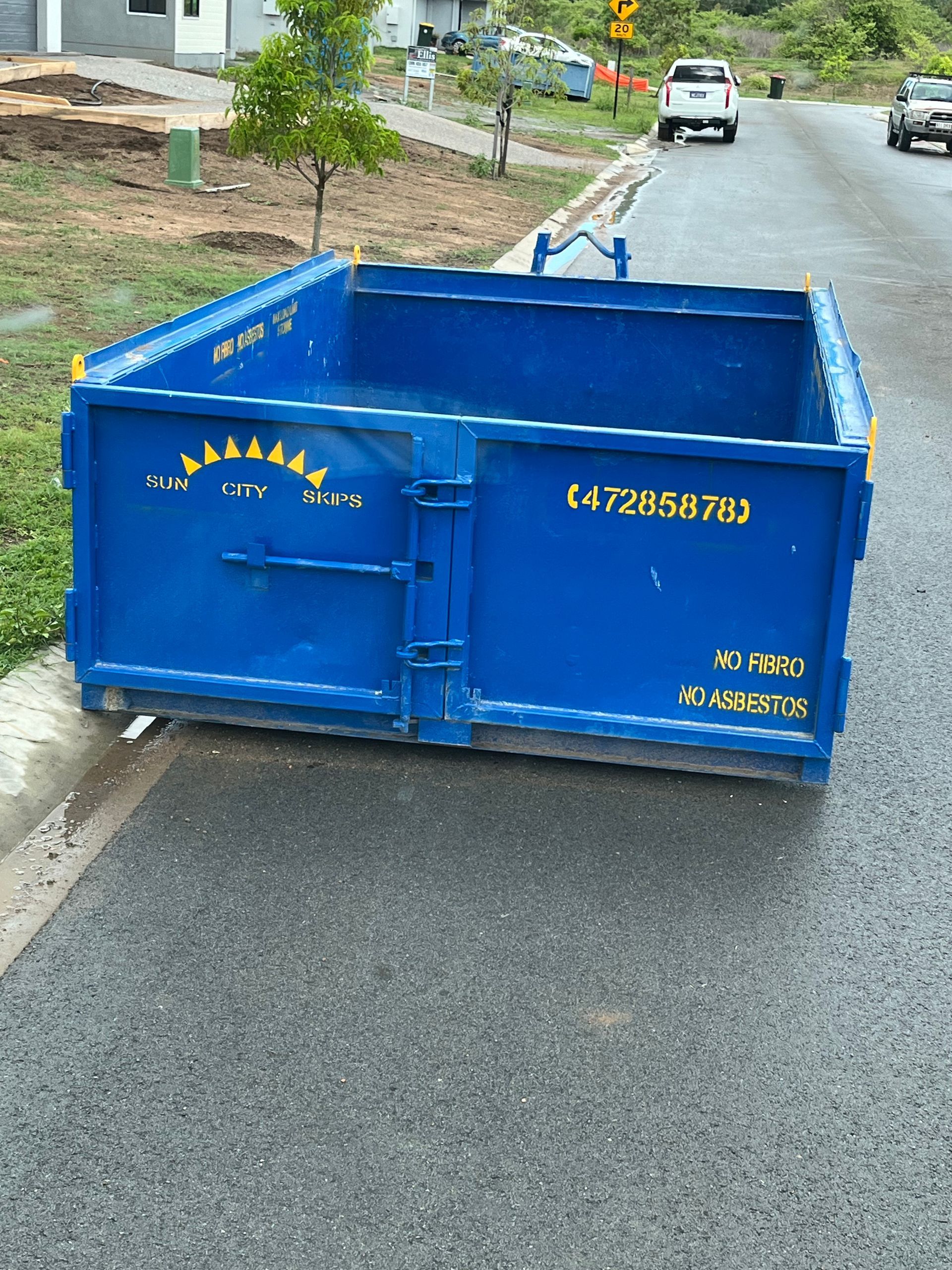 A Green Dumpster Is Filled With Trash In Front Of A Building — Sun City Skips In Bohle, QLD