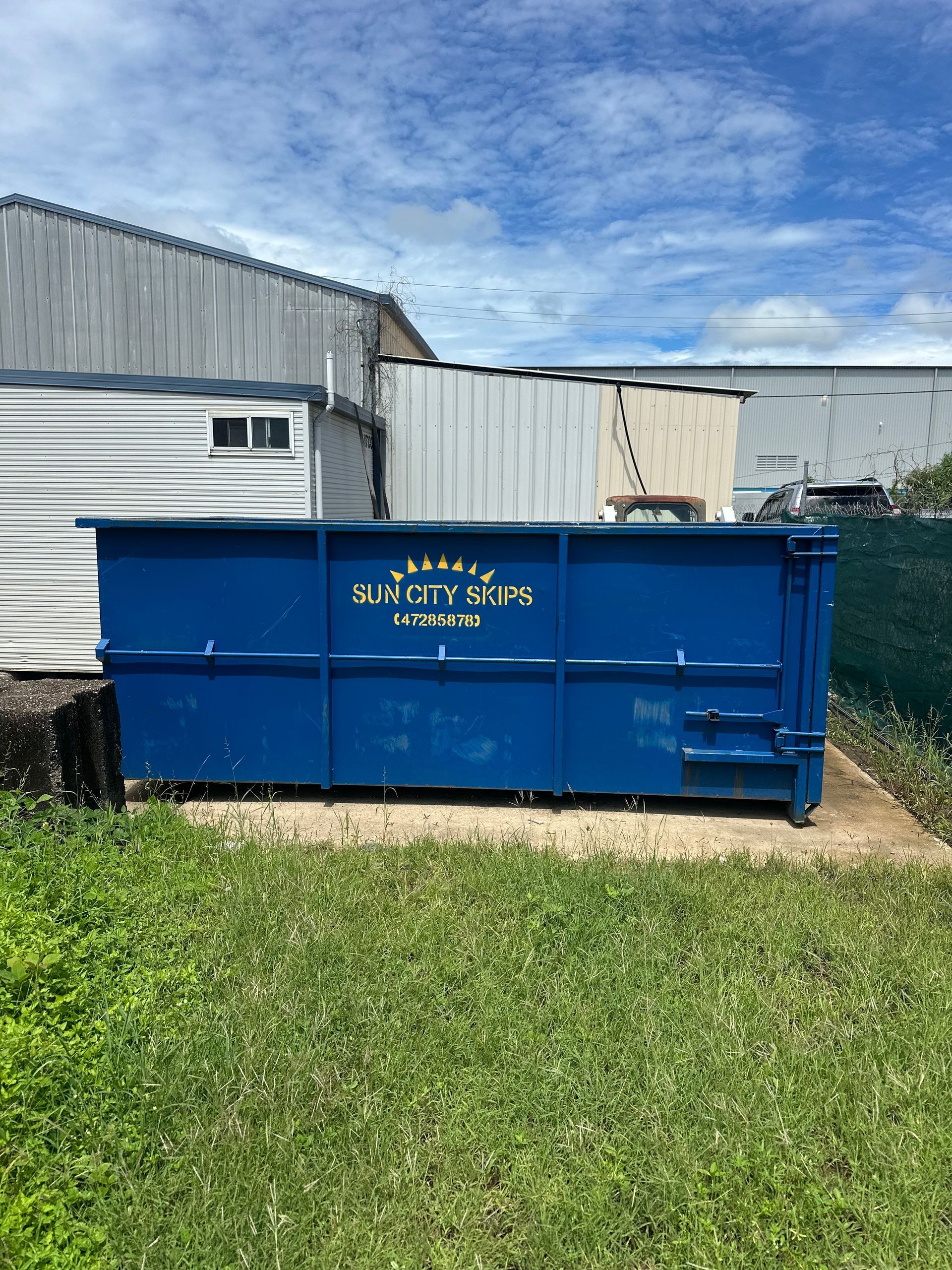 A Green Dumpster Filled With Trash Bags And A Chair — Sun City Skips In Bohle, QLD