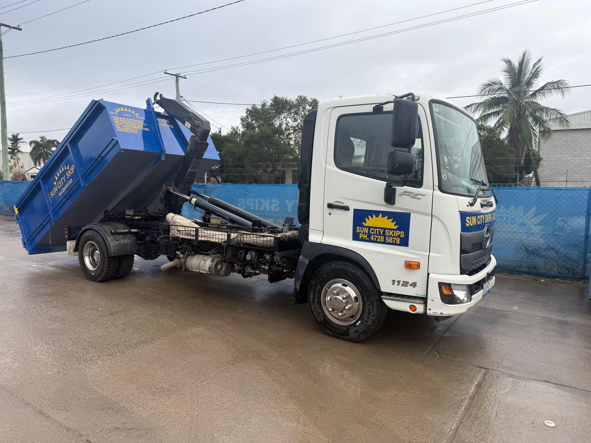 A Red Skip Bin Filled With Bricks Is In Front Of A Brick House — Sun City Skips In Bohle, QLD