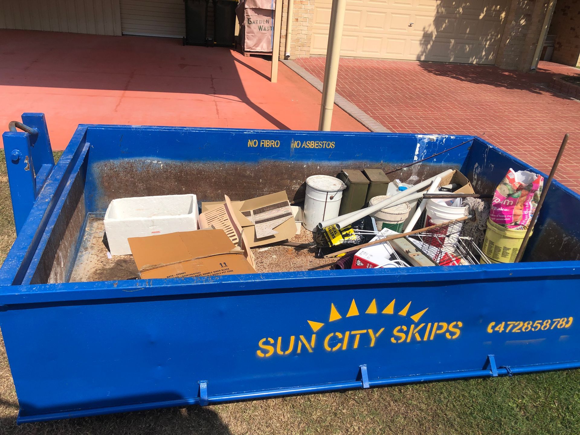 A Dumpster Is Sitting On The Side Of The Road Next To A Row Of Orange Barriers — Sun City Skips In Bohle, QLD