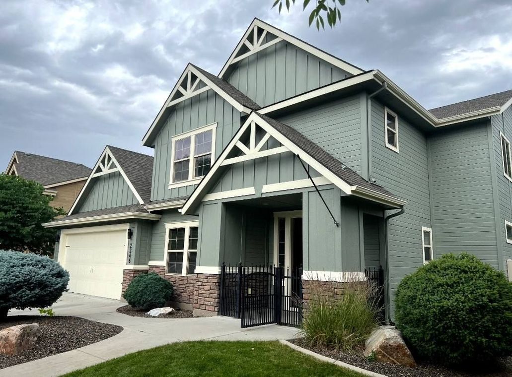 A large green house with a white trim and a gray roof.
