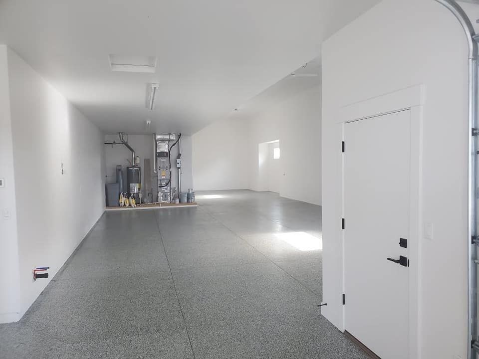 A large empty garage with a gray floor and white walls.