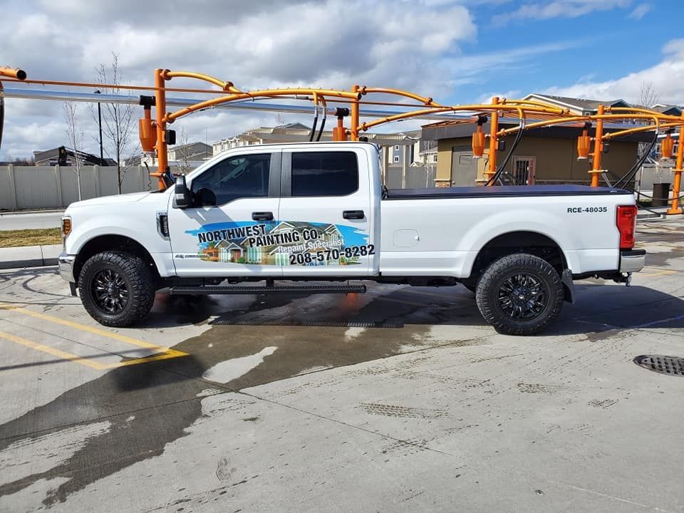 White pickup truck with colorful side graphics parked at a fuel station under orange canopy equipment
