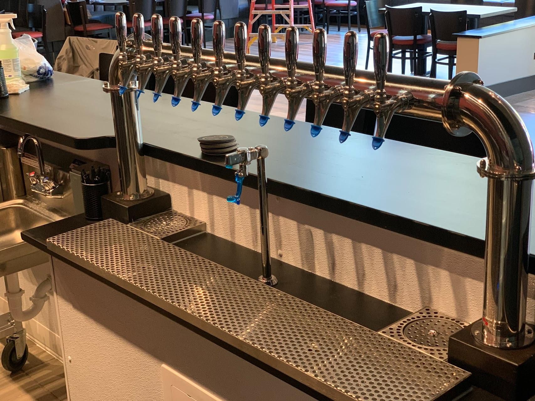A bar with a lot of beer taps and a sink.