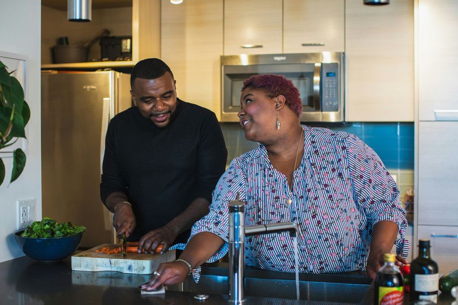A man and a woman are cooking together in a kitchen.