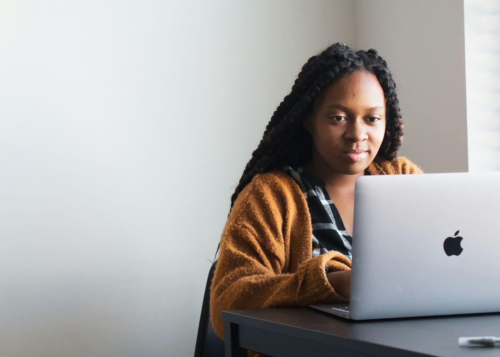 A woman is sitting at a desk using an apple laptop computer.