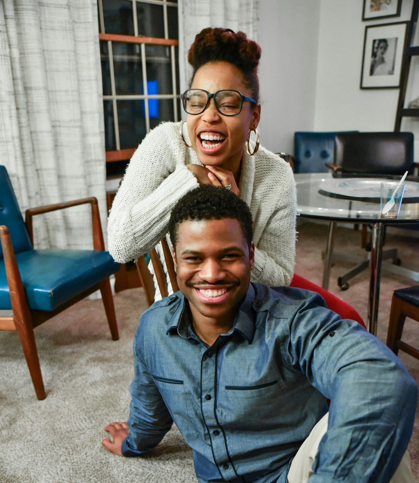A man and woman are posing for a picture in a living room