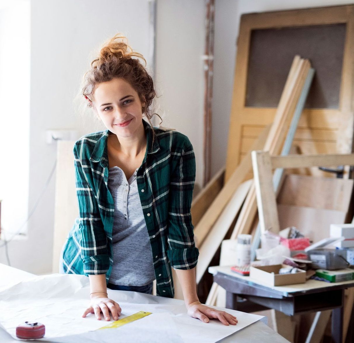 A woman in a plaid shirt is leaning on a table