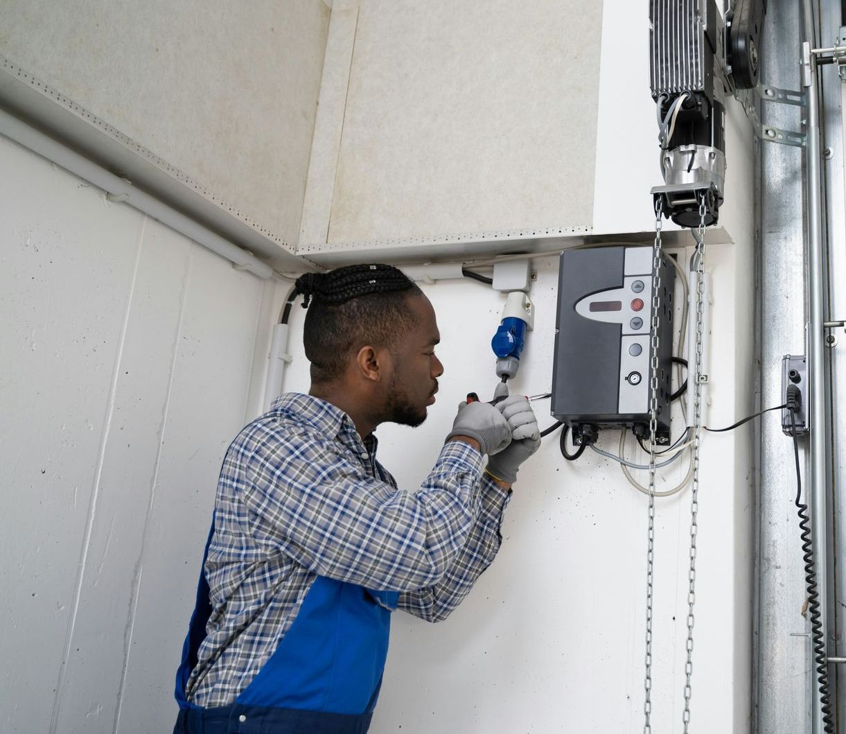 A man is working on a garage door with a screwdriver
