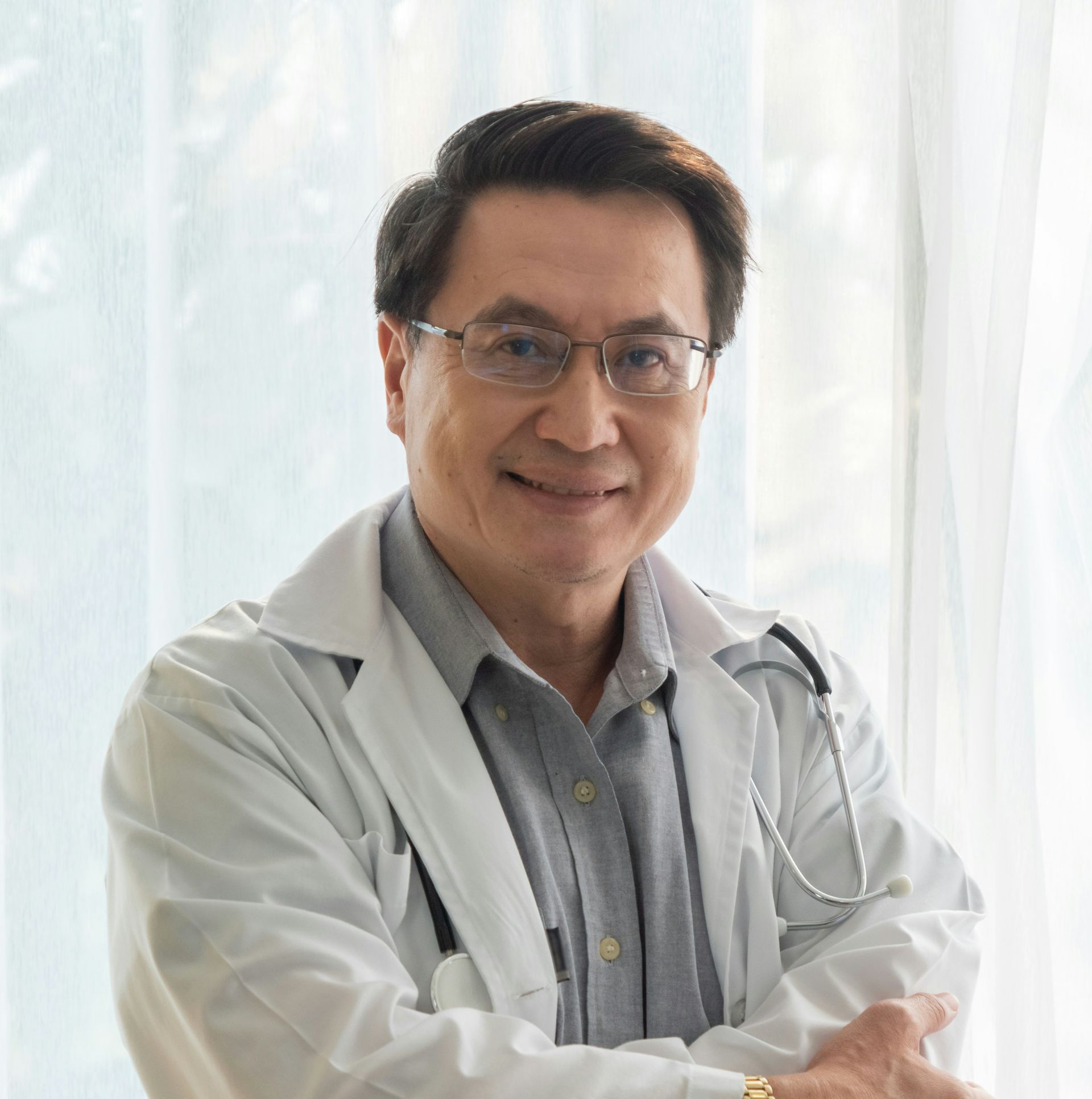 A doctor wearing glasses and a white coat with a stethoscope around his neck