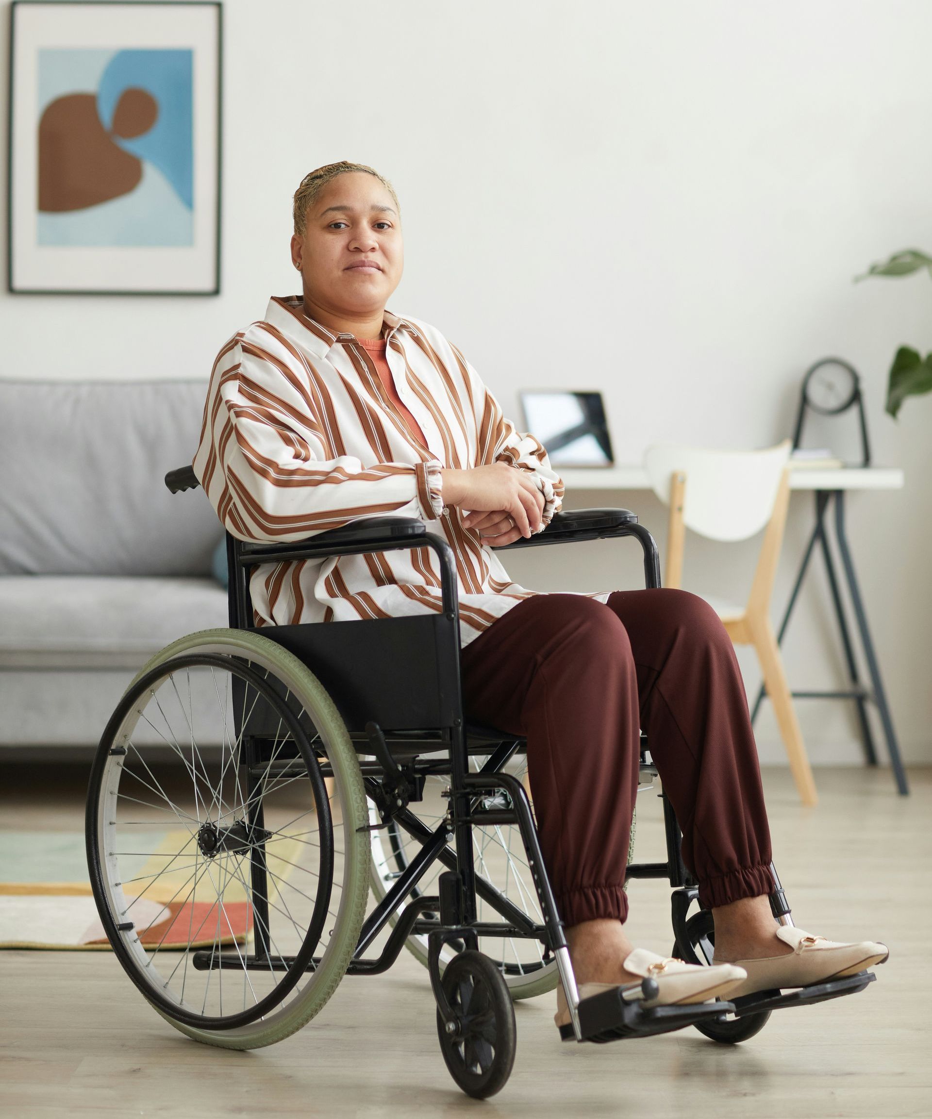 A woman is sitting in a wheelchair in a living room.