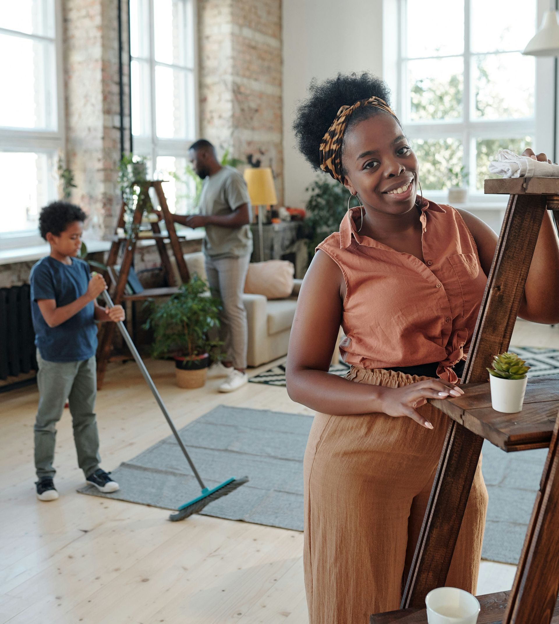 A woman is standing on a wooden ladder in a living room.