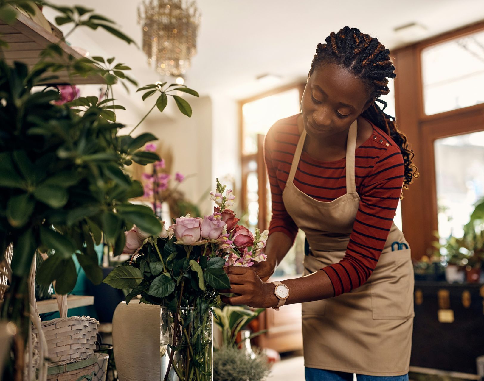 A woman is arranging flowers in a vase in a flower shop.
