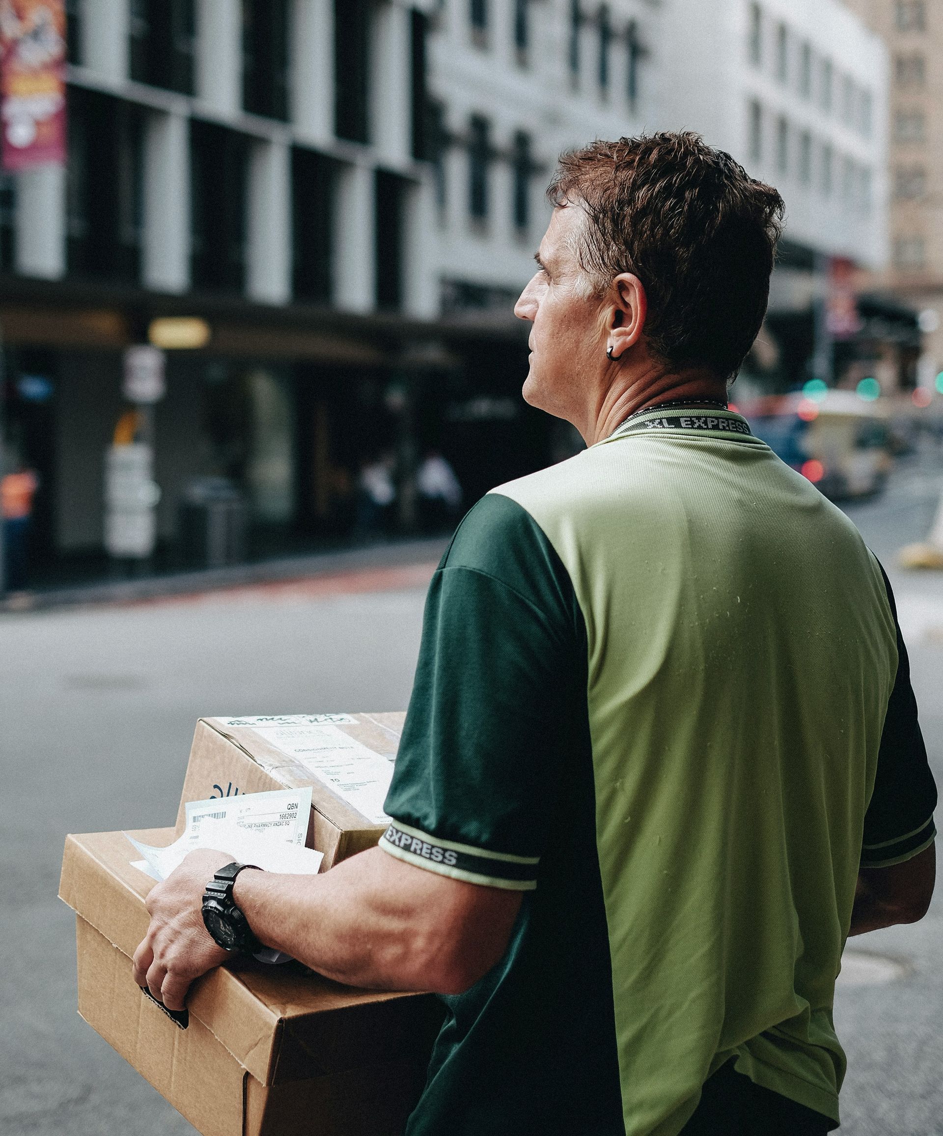 A man in a green shirt is carrying a cardboard box