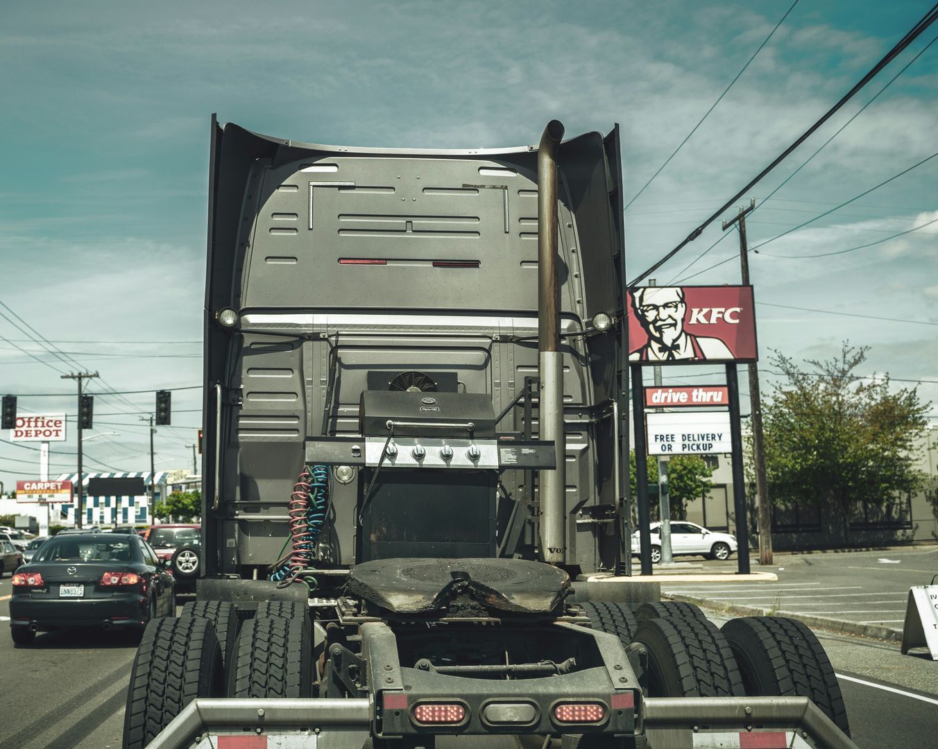 A semi truck with a kfc sign in the background