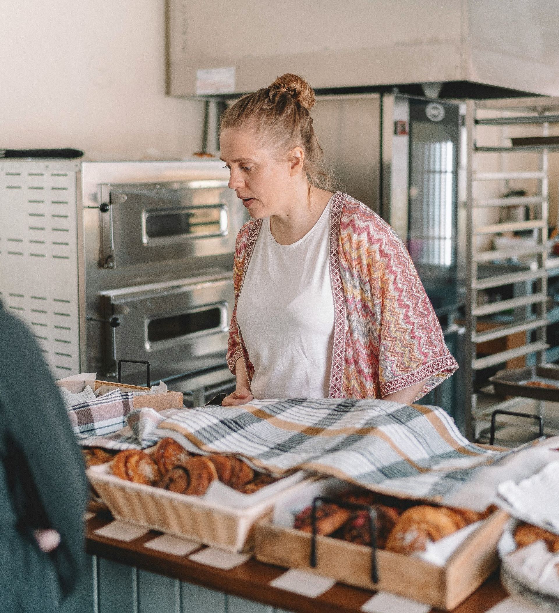 A woman is standing at a counter in a bakery