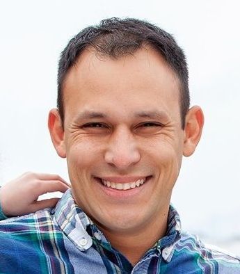 A man in a plaid shirt is smiling for the camera.