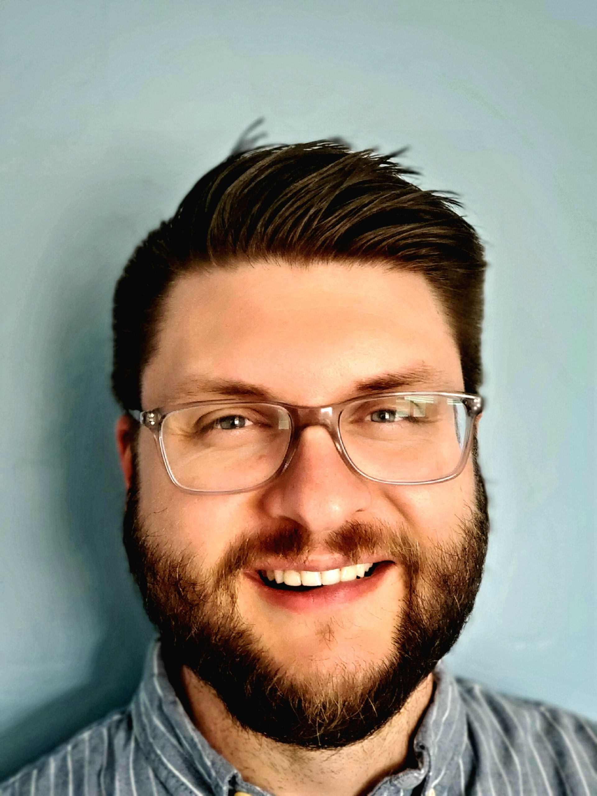 A man with a beard and glasses is smiling for the camera.