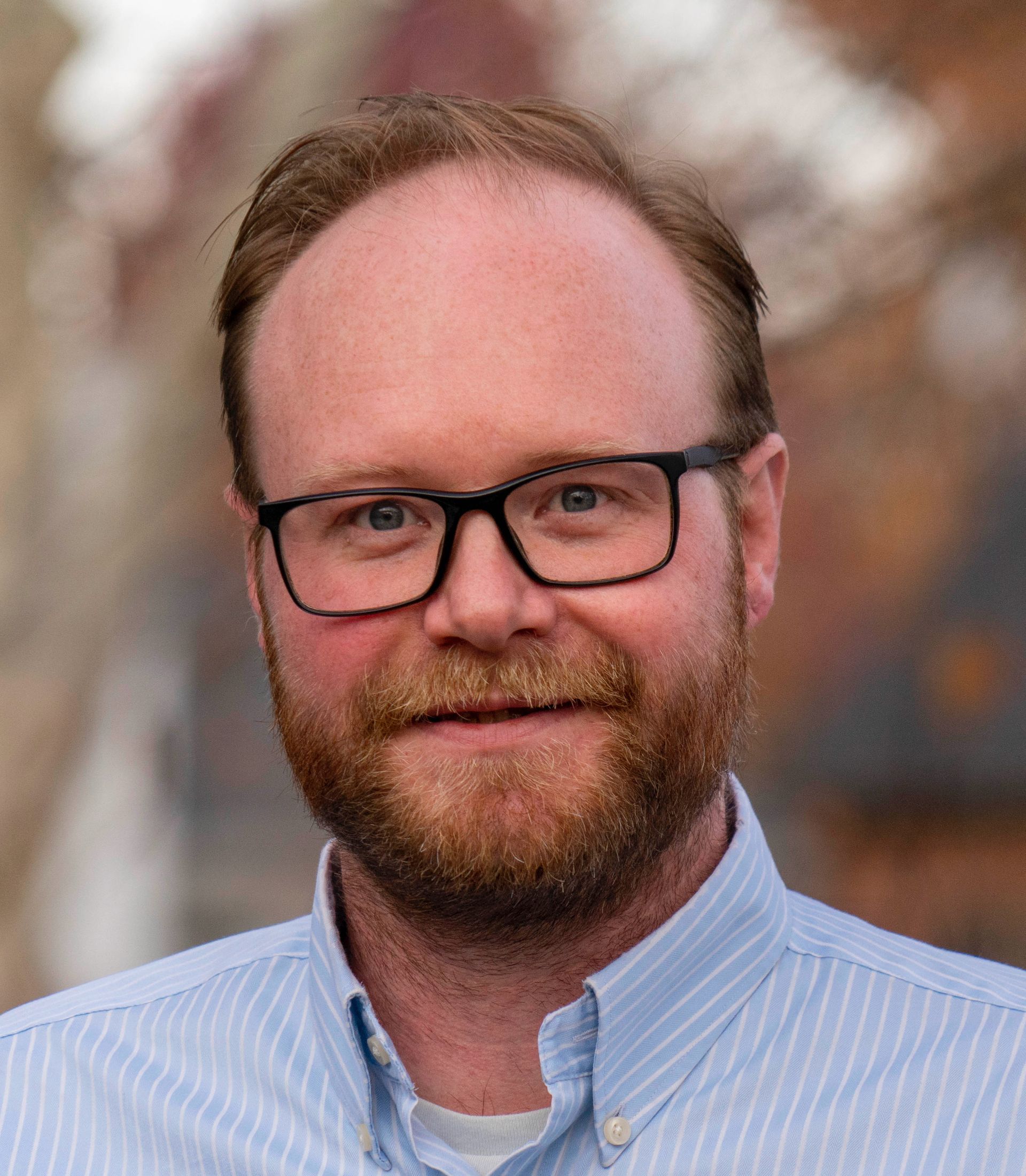 A man with a beard and glasses is smiling for the camera.