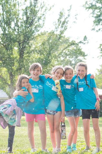 A group of young girls are posing for a picture in a park.