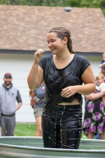 A woman is standing in a tub of water and smiling.