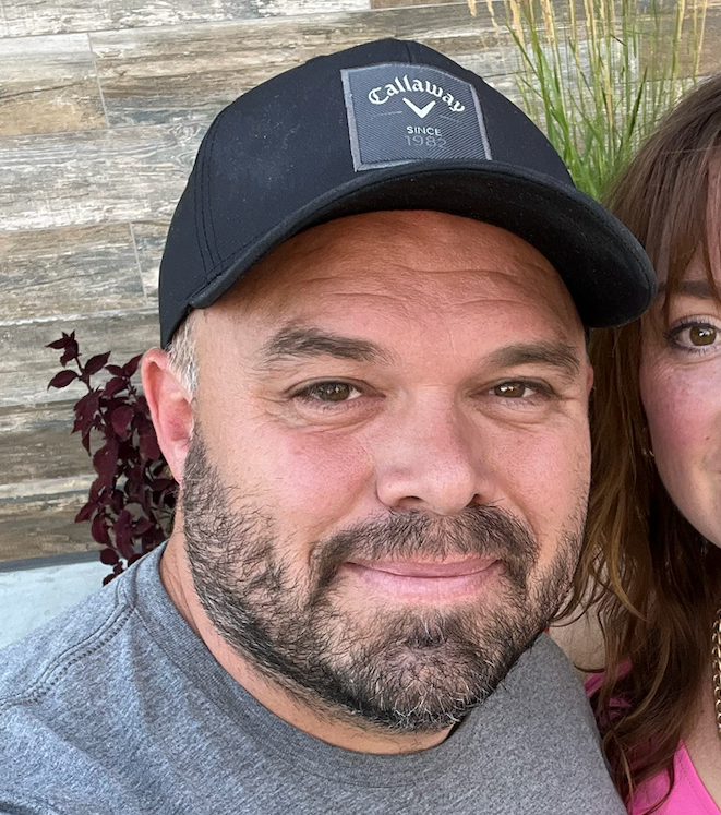 A man with a beard wearing a black hat is standing next to a woman.