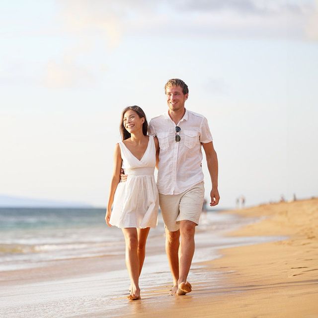 A man and a woman are walking on the beach