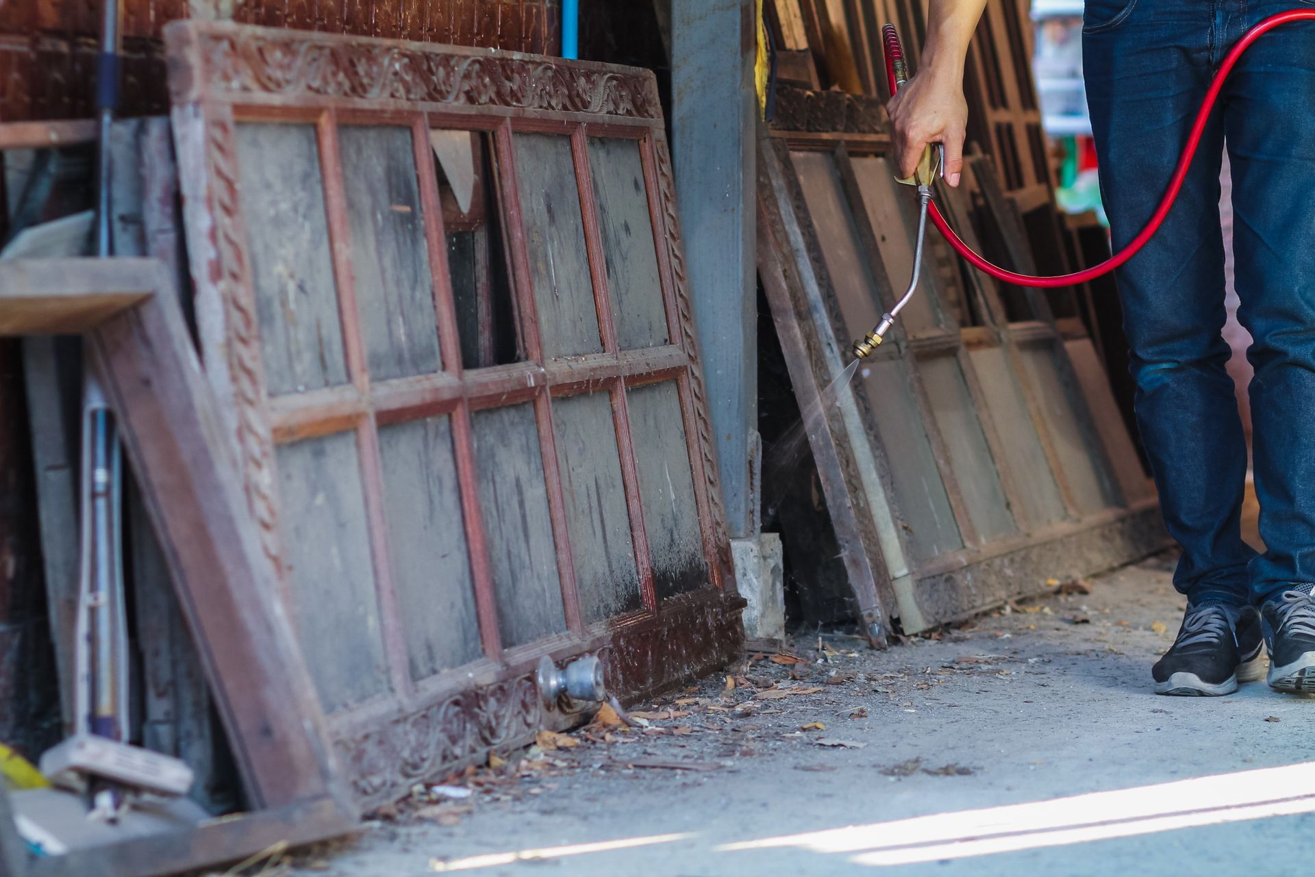 Workers moving old window frames and boards beside a dusty wall outdoors