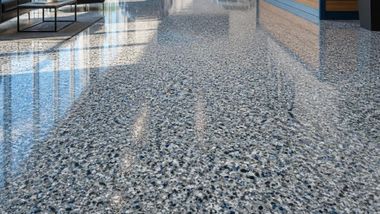Speckled gray terrazzo floor reflecting windows in a bright indoor corridor