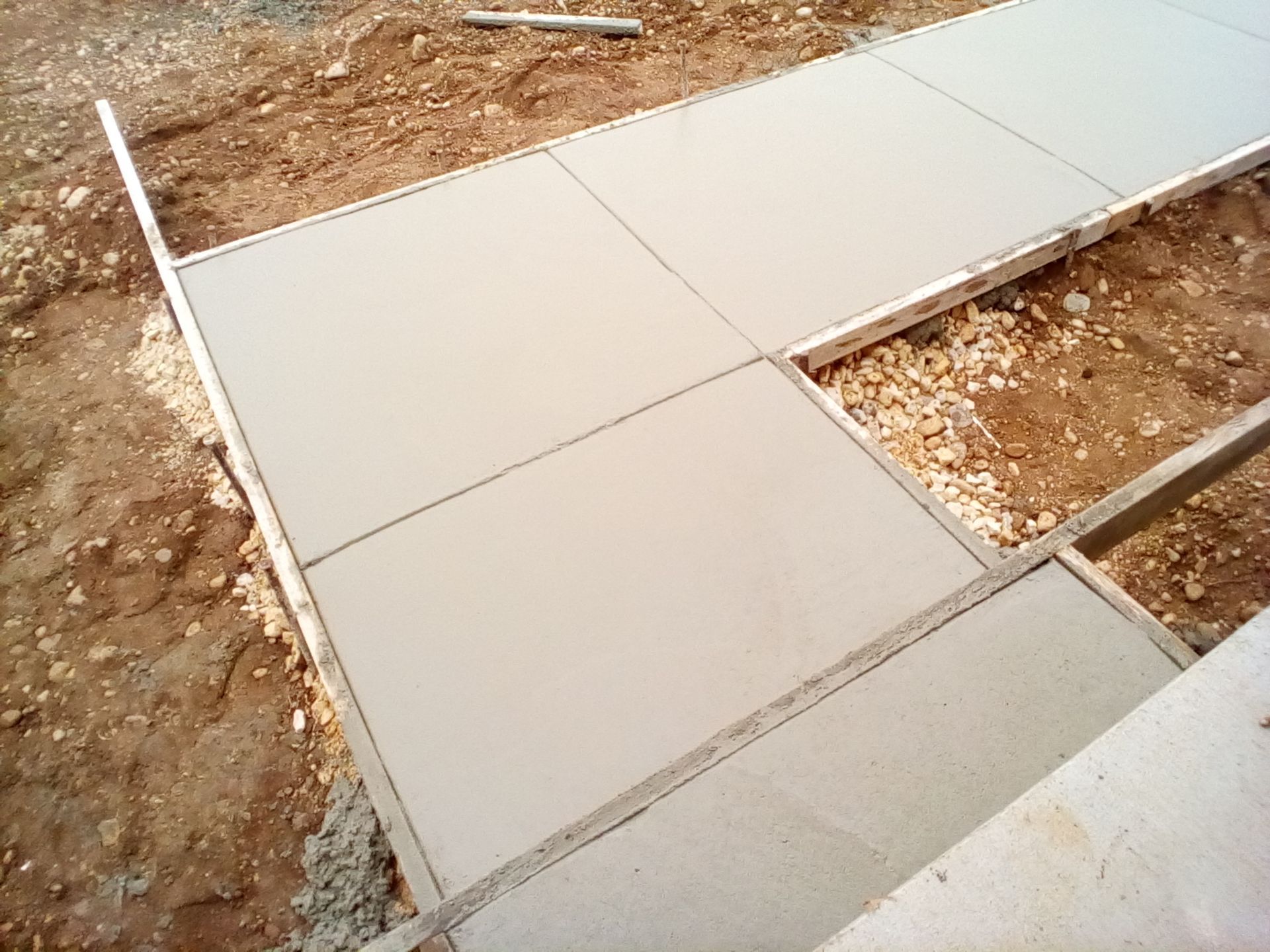 A concrete walkway is being built in the dirt