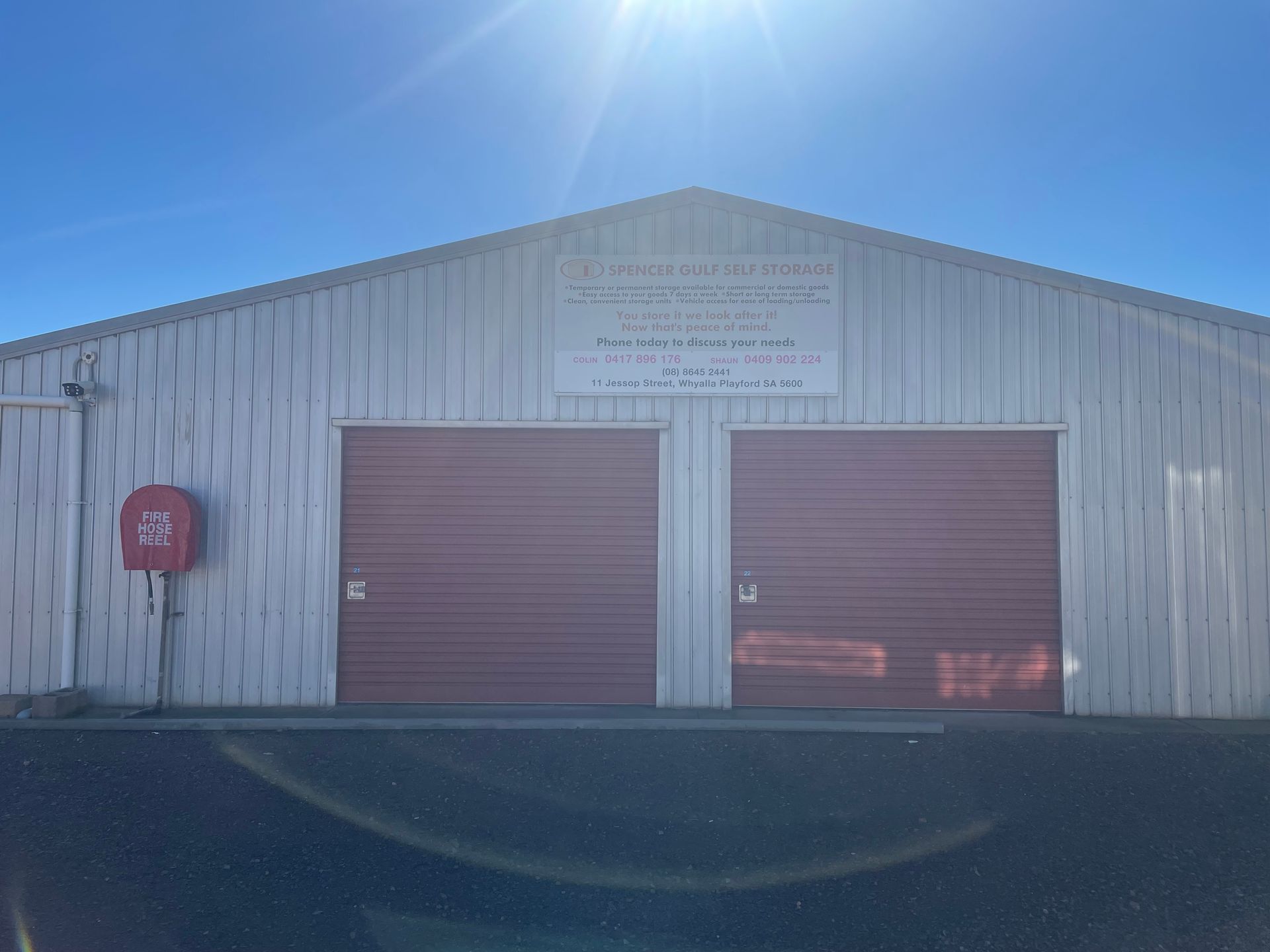 Indoor storage facility corridor with red roll-up doors and a concrete floor