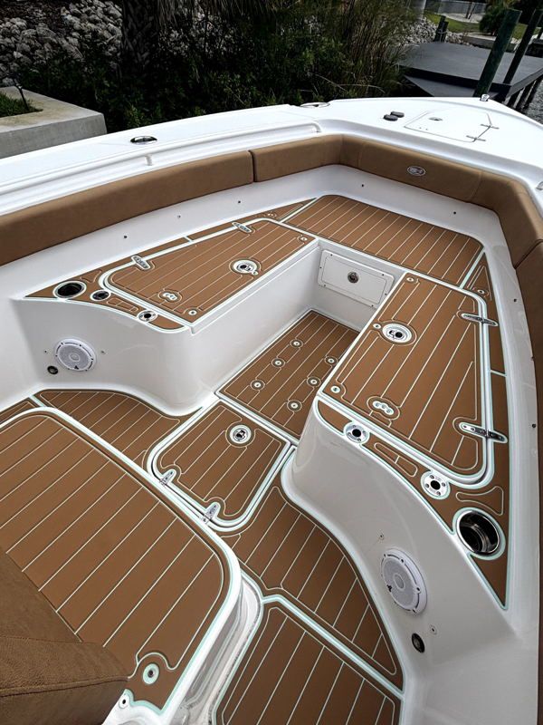 Overhead view of an open-cockpit boat layout showing geometric teak-wood flooring with white borders outlining seating