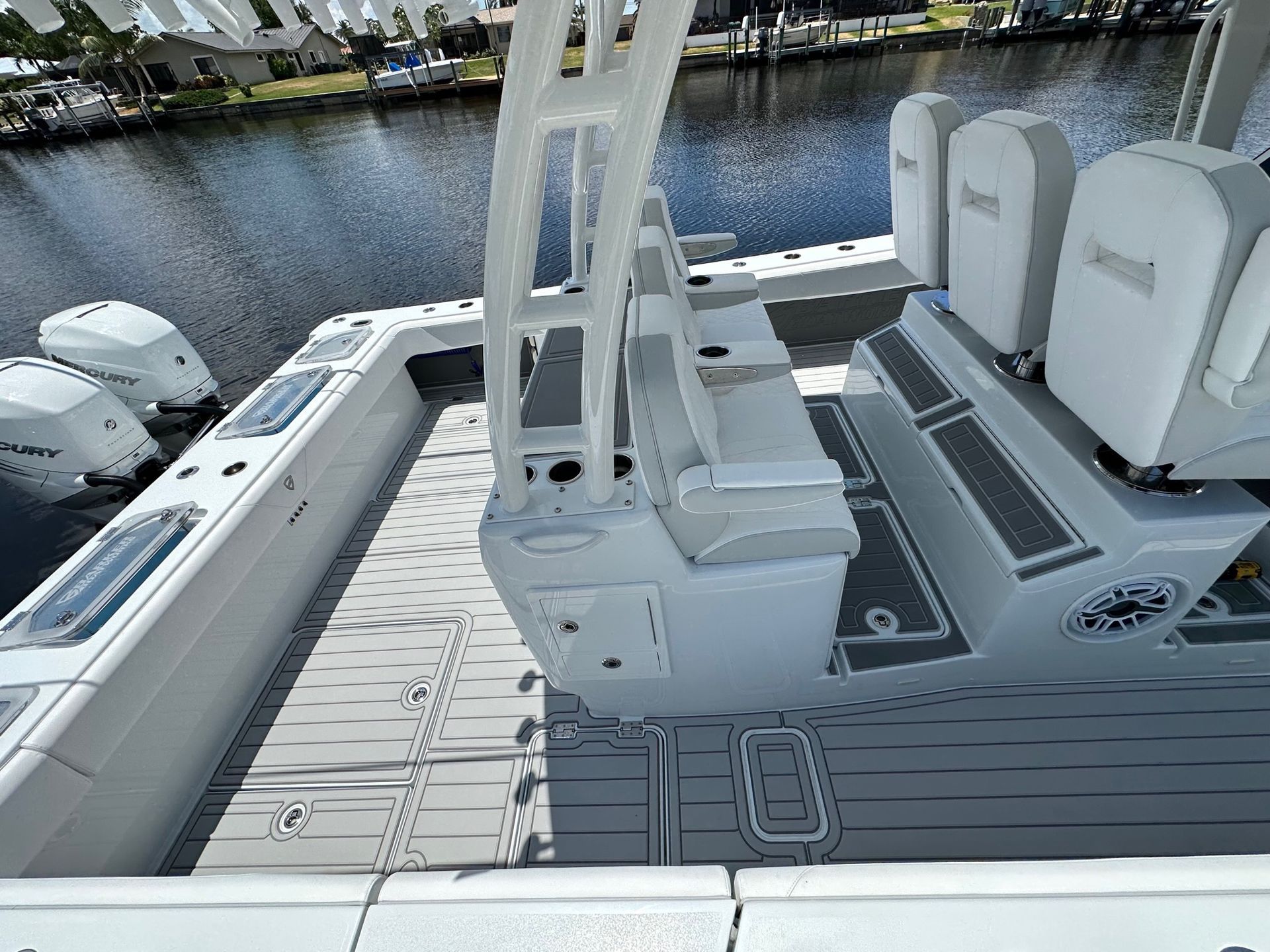 Wide-angle view of boat interior showing white vinyl seating with cushioned backrests, gray...
