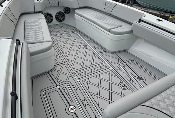 Interior cabin view of a recreational boat featuring light gray upholstered seating with quilted diamond pattern detailing