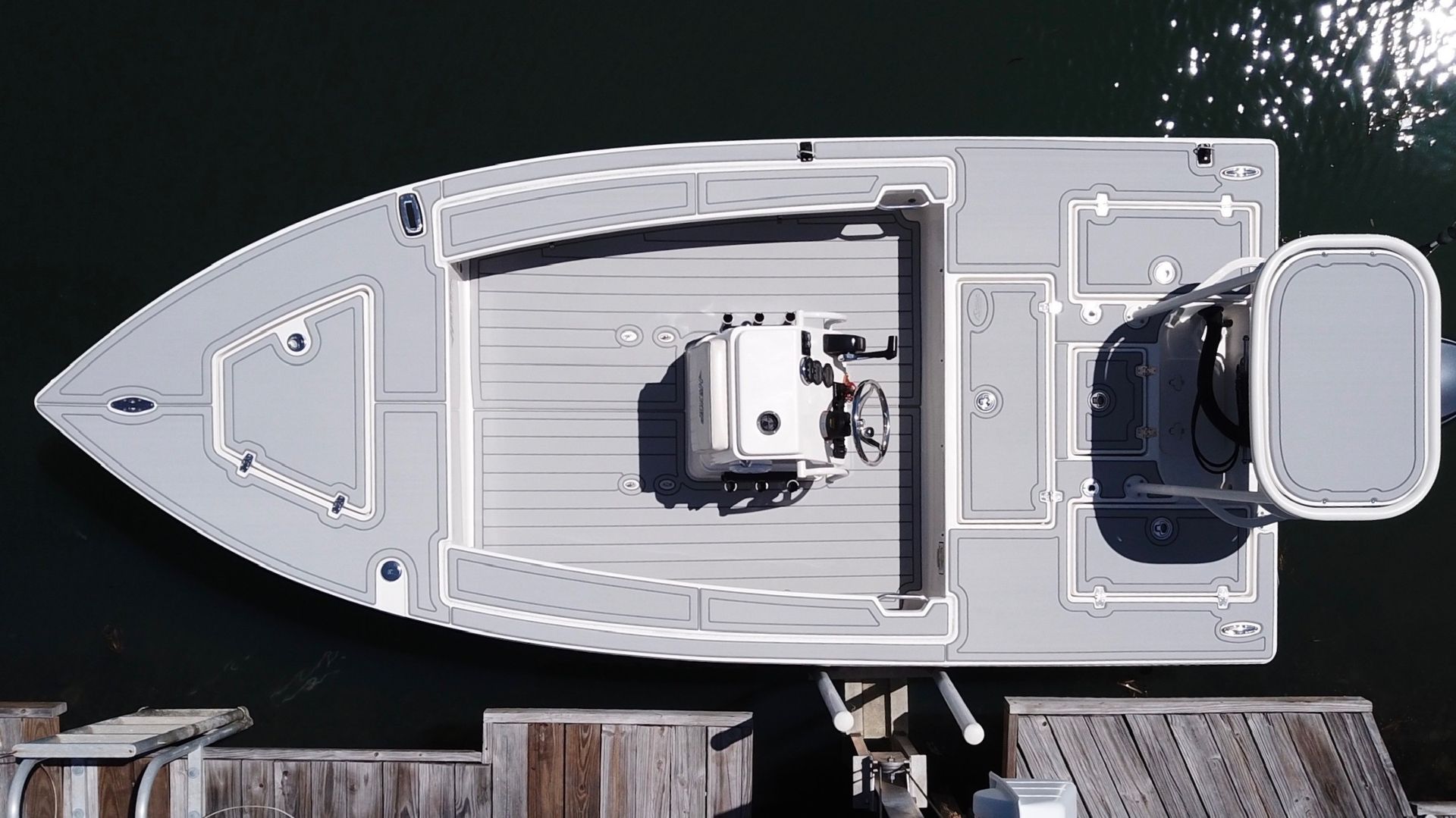 Aerial view of a white fiberglass sport fishing vessel docked at a wooden pier, photographed from...