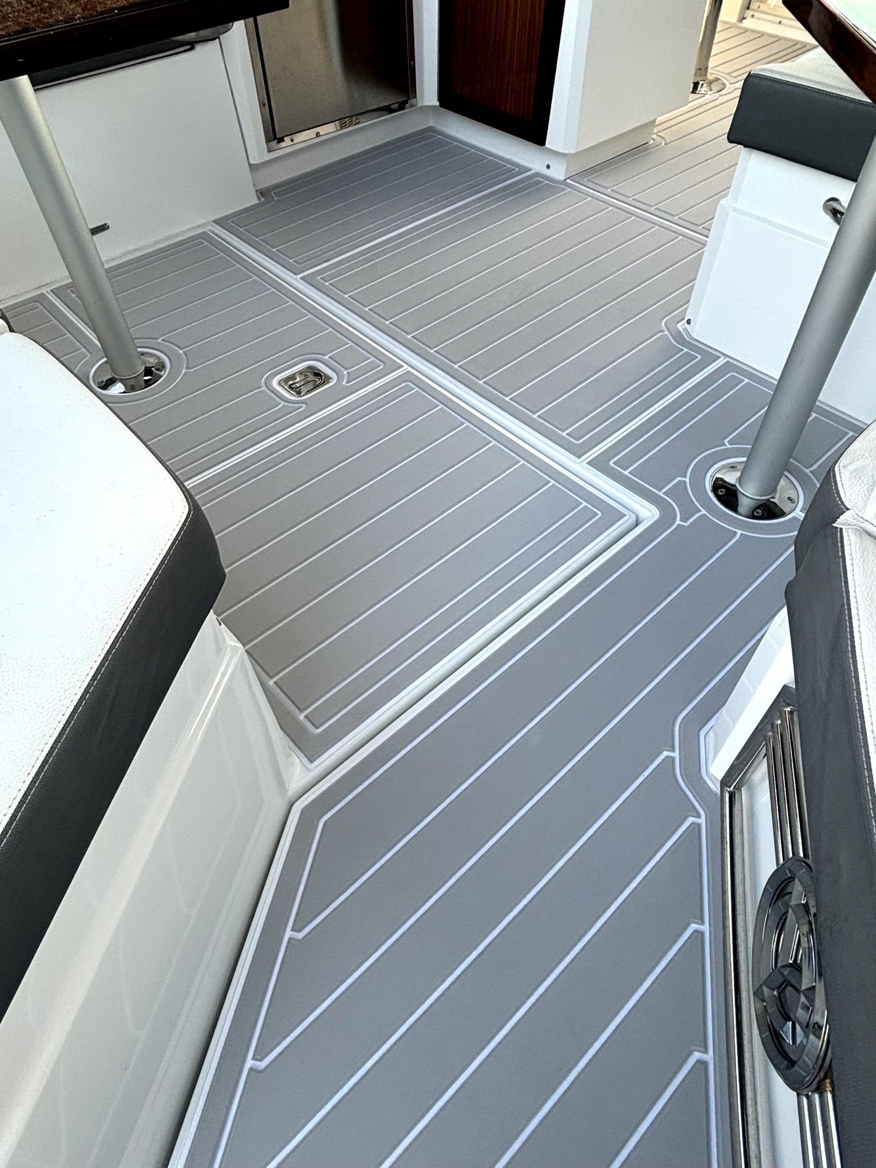 Wide-angle view of a boat's interior cabin floor showing continuous gray foam decking
